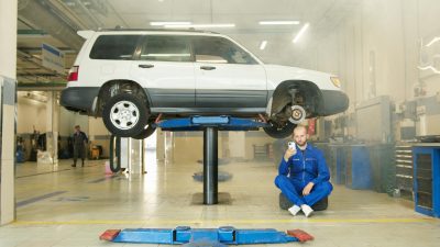 mechanic using smartphone for digital vehicle inspection in auto repair shop